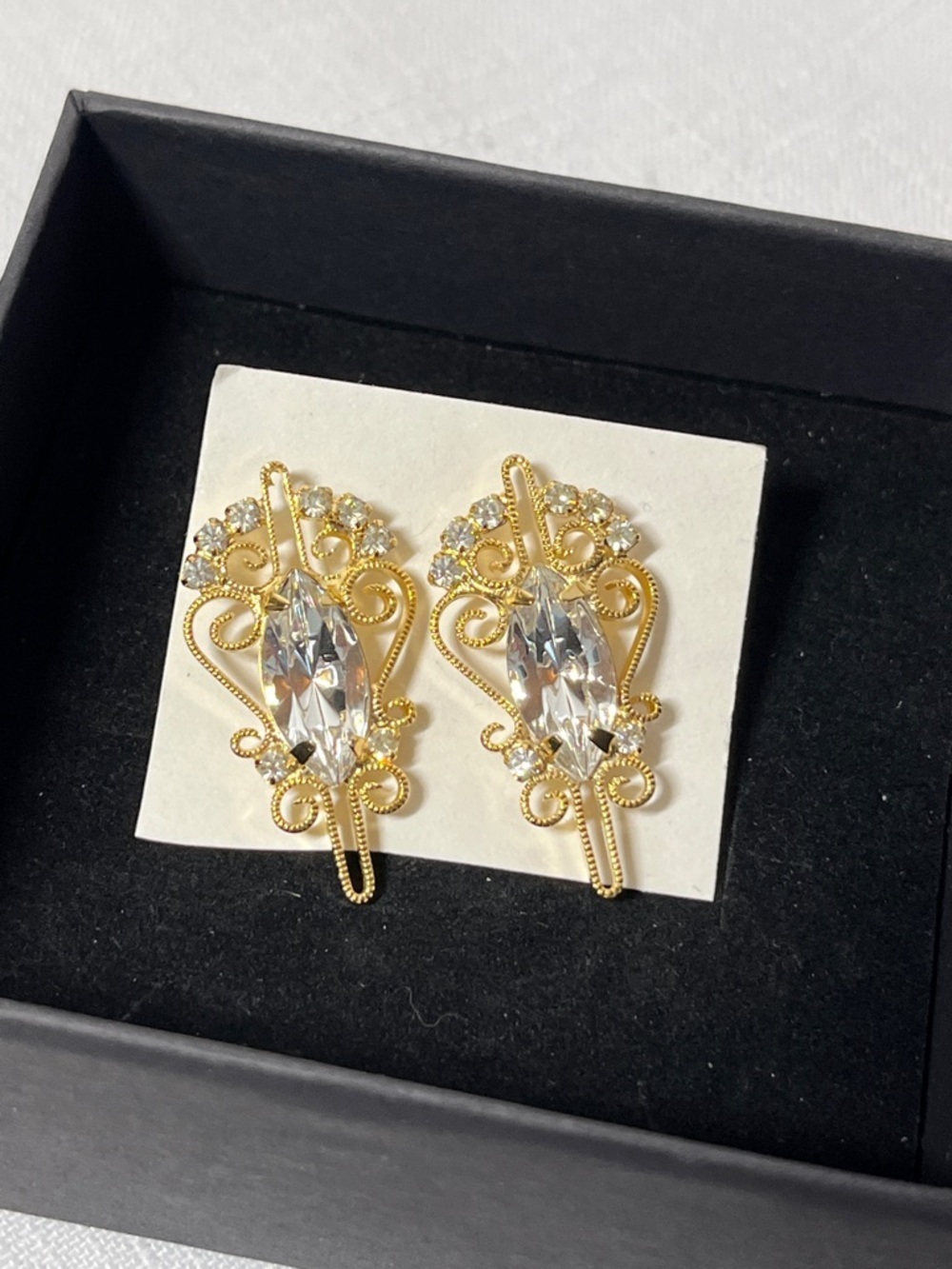 Vintage ornate gold-tone earrings with central marquise-cut rhinestones.